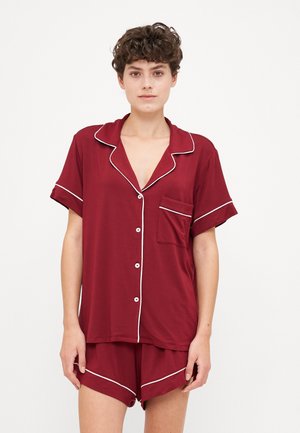Σετ πιτζάμας κοντομάνικο σε μπορντό χρώμα από μαλακό ύφασμα, με λευκές λεπτομέρειες και τσέπη στο πουκάμισο. Περιλαμβάνει αντίστοιχες σορτς με παρόμοια χαρακτηριστικά.