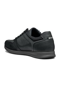 Chaussure de sport noire combinant cuir et daim, forme arrondie, dessus texturé et accents matériels minimaux.
