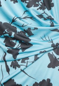 Lichtblauwe stof met zwarte bloemmotieven, met een gladde textuur en subtiele glans. Het ontwerp bevat uiteenlopende vormen en vloeiende lijnen.