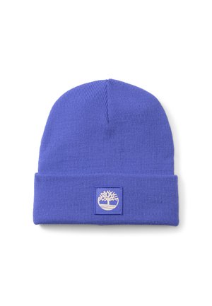 Purple knit beanie with a folded cuff, featuring a square patch adorned with a white tree logo. Soft texture, simple design.
