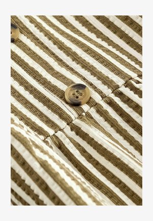 Tissu rayé olive et crème avec une texture grossière. Deux boutons ronds marbrés sont visibles le long de la couture.