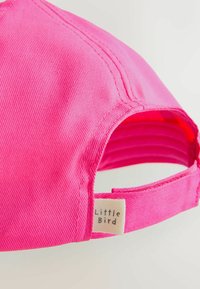 Casquette de baseball en coton rose avec des détails cousus, une sangle ajustable et une étiquette en tissu portant la marque "Little Bird".