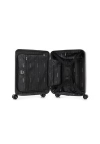 Valigia rigida di colore argento. L'interno aperto presenta rivestimento in tessuto nero con motivo a righe diagonali, due tasche con zip e cinghie di compressione.