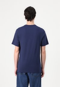 Mørkeblå bomulds t-shirt med korte ærmer og rund halsudskæring, synlig syning langs sømmene og en afslappet pasform.