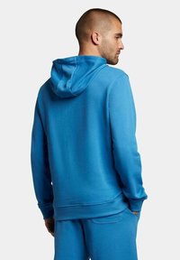 Felpa con cappuccio di un blu intenso, caratterizzata da una superficie morbida, una vestibilità comoda e polsini a costine. Cuciture visibili e tasca a marsupio.