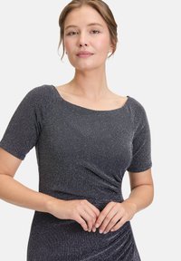 Błyszcząca granatowa sukienka z krótkimi rękawami, okrągłym dekoltem i marszczonym detalem w talii. Dopasowany krój z elastycznego materiału o metalicznym połysku.