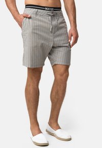 Gråstribede shorts med en sort elastisk talje, der har "INDICODE". Fremstillet af letvægtsstof, med en afslappet pasform og sidelommer.
