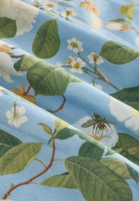 Bomuldsstof med en blå baggrund med grønne blade, hvide blomster og en detaljeret bi med gule striber.