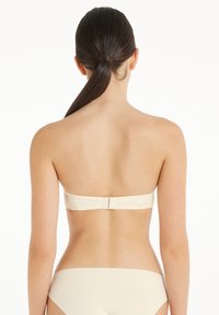 Beige trägerloser BH mit glatter Stoffoberfläche, ausgestattet mit einem Hakenschluss hinten und nahtlosem Design an den Kanten.