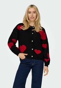 Svart cardigan med röda hjärtmönster, rund halsringning och silverf�ärgade hjärtformade knappar. Ribbad ärm- och fållkant ger textur.