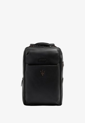 Mochila de cuero negro con acabado texturizado, cuenta con un asa superior, bolsillo frontal con cremallera y un logotipo metálico como emblema.