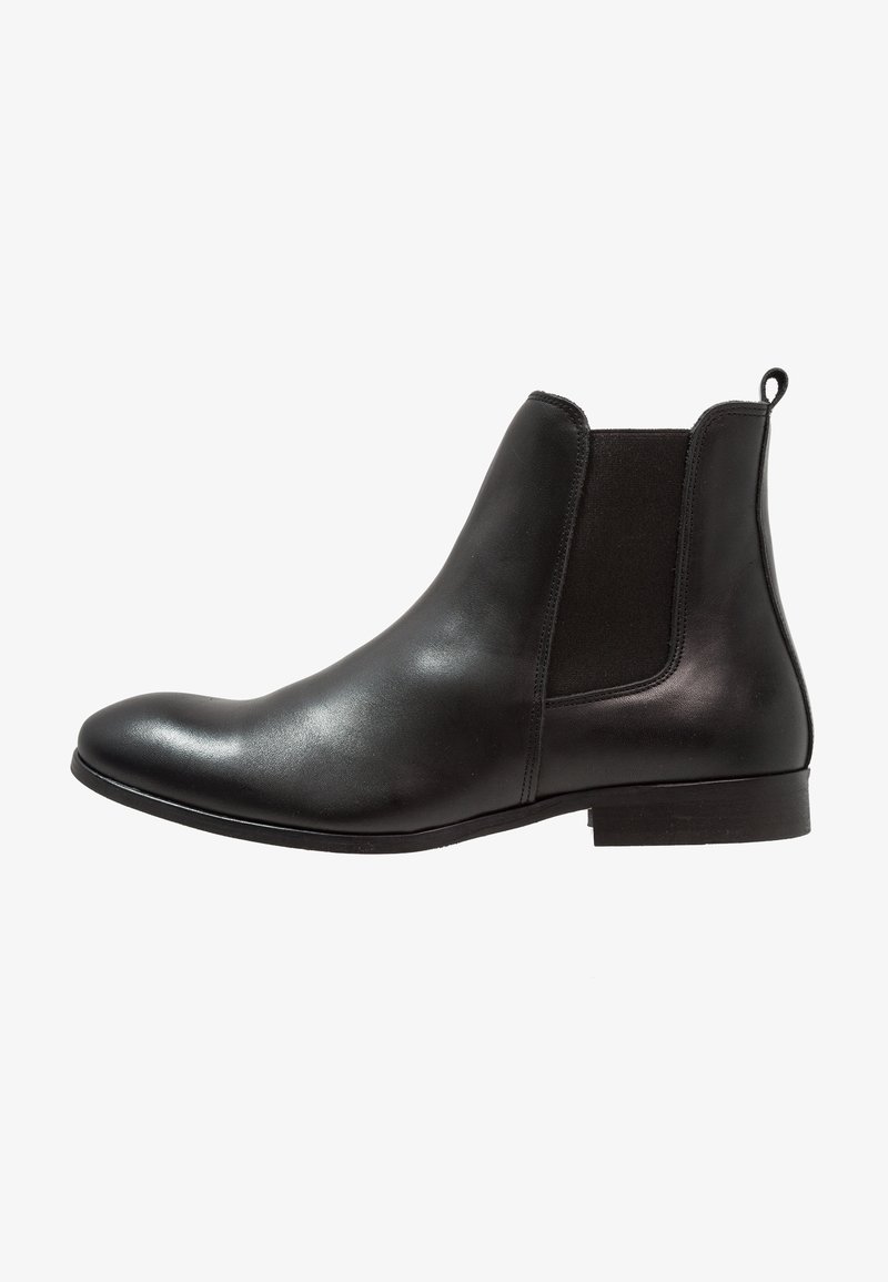 Bottine Chelsea en cuir noir avec panneau latéral élastique, languette à l’arrière et petit talon empilé.