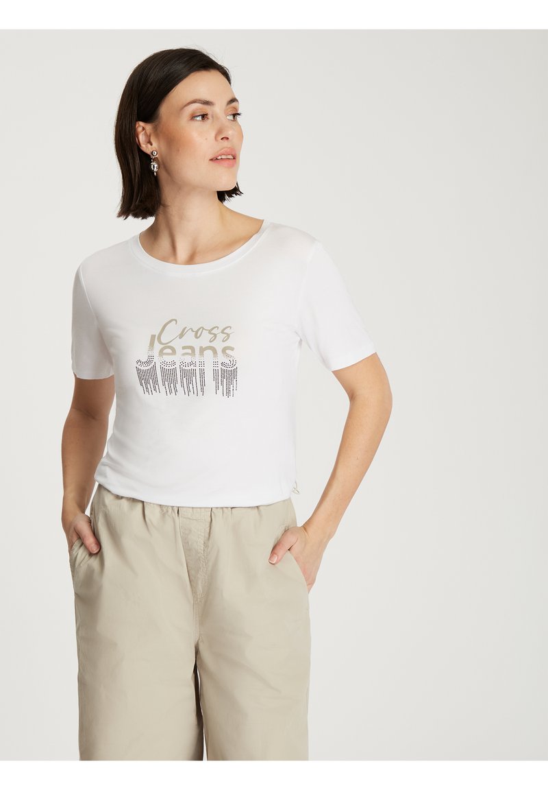 Biała koszulka z krótkim rękawem z metalicznym nadrukiem "Cross Jeans" w odcieniach złota i srebra. Miękki, gładki materiał o luźnym kroju.