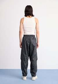 Sorte, teksturerede cargos med elastisk talje, med sidelommer og en løstsiddende pasform, parret med en hvid tanktop.