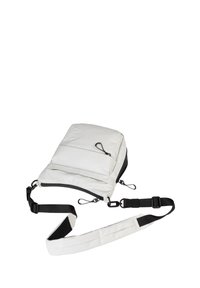 Zaino bianco leggero realizzato in tessuto, dotato di un compartimento principale con zip, spallaccio nero regolabile e ganci laterali per accessori.