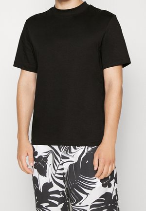 Czarny t-shirt z krótkim rękawem i okrągłym dekoltem, wykonany z bawełny, zestawiony z białymi szortami w czarny kwiatowy wzór.