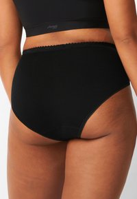 Mutande nere a vita alta realizzate in cotone morbido. Presentano un bordo in pizzo ondulato lungo l'elastico in vita e un design senza cuciture per il massimo comfort.