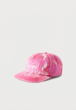 Roze baseballpet met witte "Aries" tekst en vlam- en wortelmotieven op voor- en zijpanelen tegen een effen achtergrond.