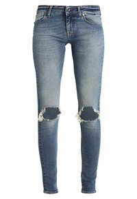 Niebieskie wąskie dżinsy z wyblakłym praniem i postrzępionymi dziurami na obu kolanach, z przednimi kieszeniami i zapięciem na guzik.
