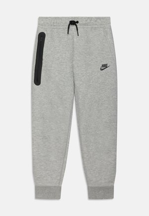 Pantalones de chándal grises hechos de una tela suave con un corte ajustado. Cuentan con una cinturilla elástica, un bolsillo con cremallera negra y el logotipo de Nike negro en el muslo.