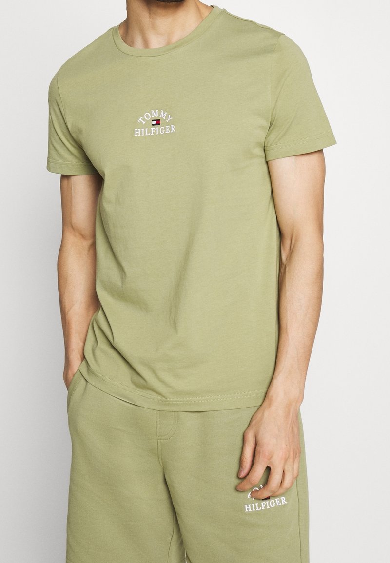 Camiseta de manga corta en color verde oliva, hecha de algodón, con un escote redondo y el logotipo bordado de "Tommy Hilfiger" en el pecho.