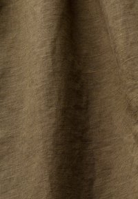 Tissu marron texturé avec un motif de tissage visible et des plis doux créant des ombres subtiles et de la profondeur.