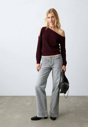 Bordo pulover s izrezom bez ramena i rebrastim uzorkom, sive široke traperice s ukrasnim šavovima, crna torba i crne cipele. Glatke teksture, ležeran dizajn.