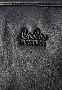 Black leather material featuring a textured surface. The embossed logo reads "lala BERLIN," prominently displayed at the center.