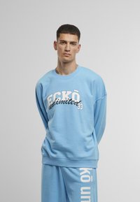 Felpa azzurra chiara con vestibilità morbida, colletto rotondo e maniche lunghe; presenta una scritta in bianco audace "ECKO unlimited 33" sul davanti.