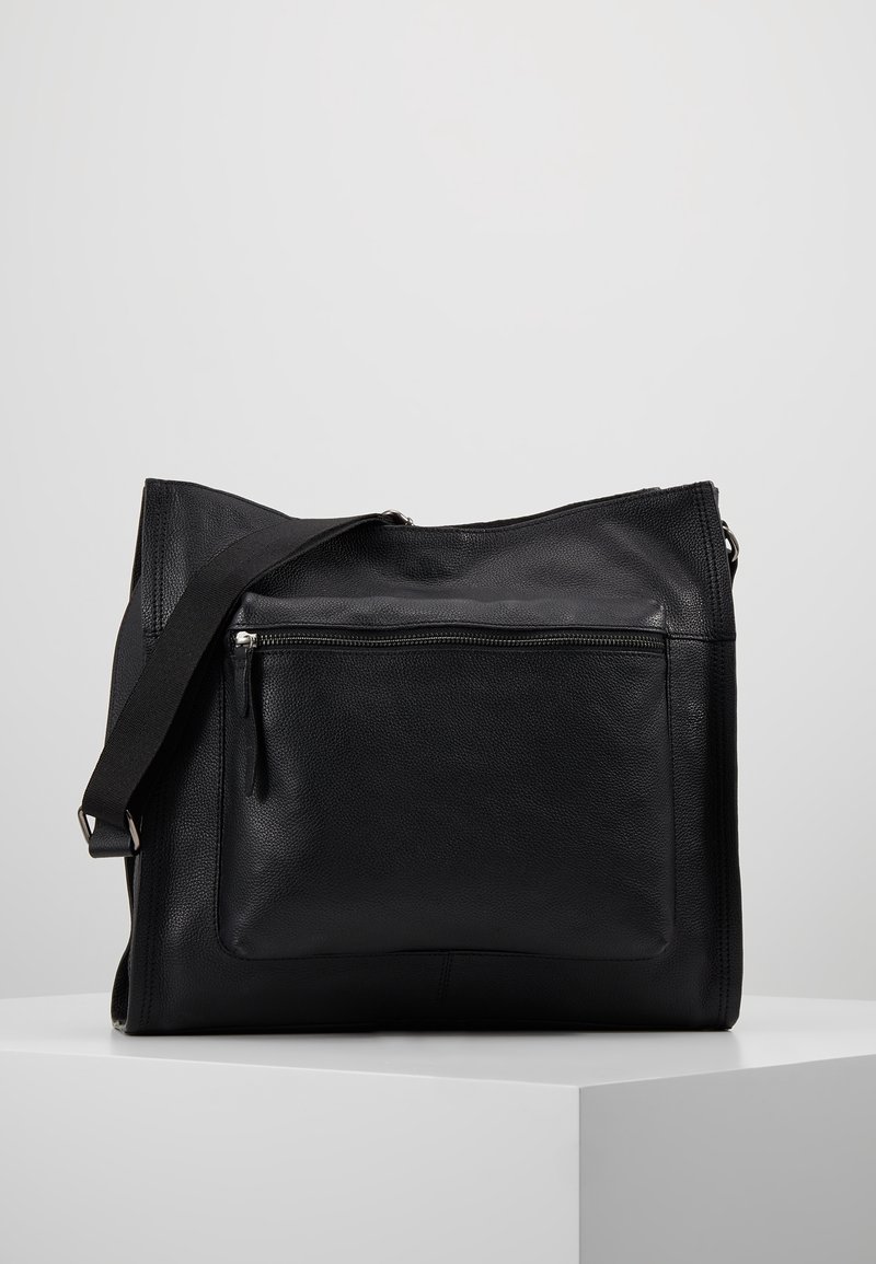 Sac messager en cuir noir avec une finition texturée, doté d'une poche zippée à l'avant et d'une bandoulière réglable. Design minimaliste avec des lignes épurées.