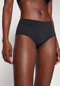 Black high-waisted briefs made of smooth fabric, featuring a wide waistband and subtle stitching details. Designed for comfort and coverage.