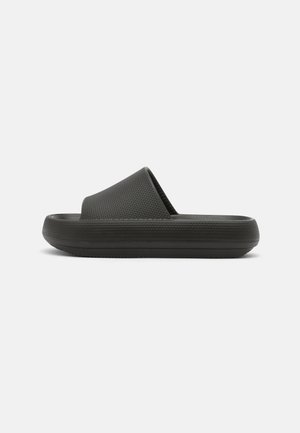 Sandales noires à enfiler avec une bride texturée et une semelle plate et rembourrée. Le design est minimaliste avec une finition lisse et sans ornements.