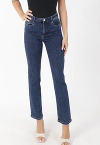 Jean en denim taille haute de couleur bleu foncé avec une coupe droite et un style à cinq poches. Le tissu présente une finition lisse avec une légère texture.