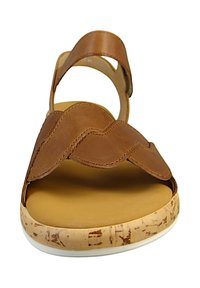 Brown leather sandal with scalloped straps, cushioned yellow footbed, and a textured cork outsole. Features a white edge trim.