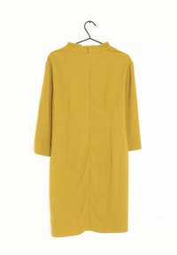 Senapsgul klänning med hög krage, trekvartslånga ärmar och dragkedja baktill. Slät tyg och ren, minimalistisk design.