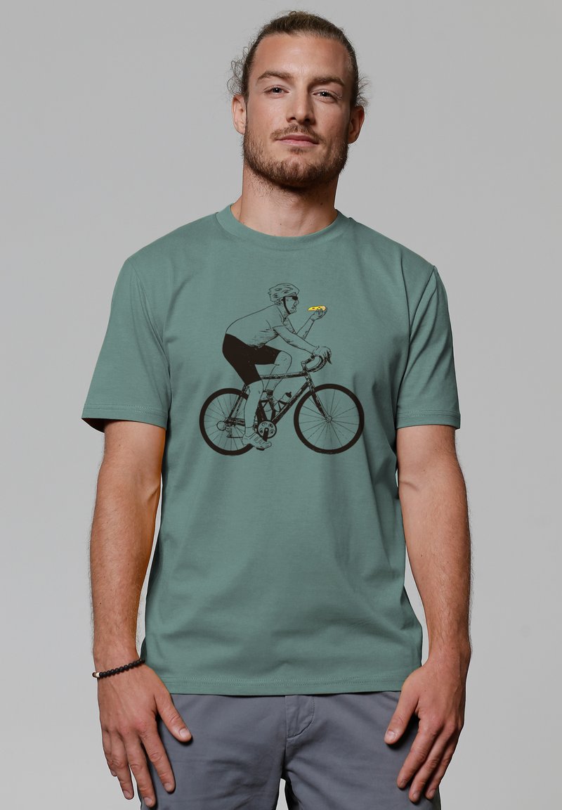T-shirt vert menthe avec un graphique d'un cycliste tenant une voiture jaune. Manches courtes, en coton, coupe décontractée et design simple.