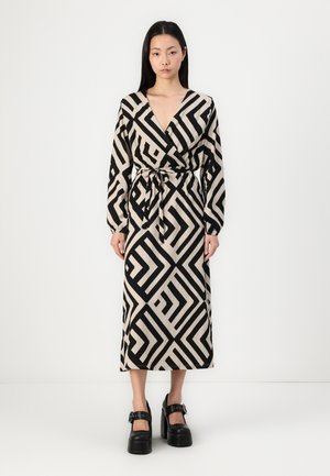 Langes Wickelkleid aus beigem Stoff mit einem auffälligen schwarzen geometrischen Muster, das mit einem Bindegürtel in der Taille gesichert ist und lange Ärmel hat.