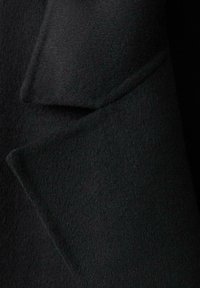 Czarna wełniana tkanina o miękkiej, teksturowanej powierzchni, z konstrukcyjnym kołnierzem i kątowymi klapami dla dopasowanego wyglądu.