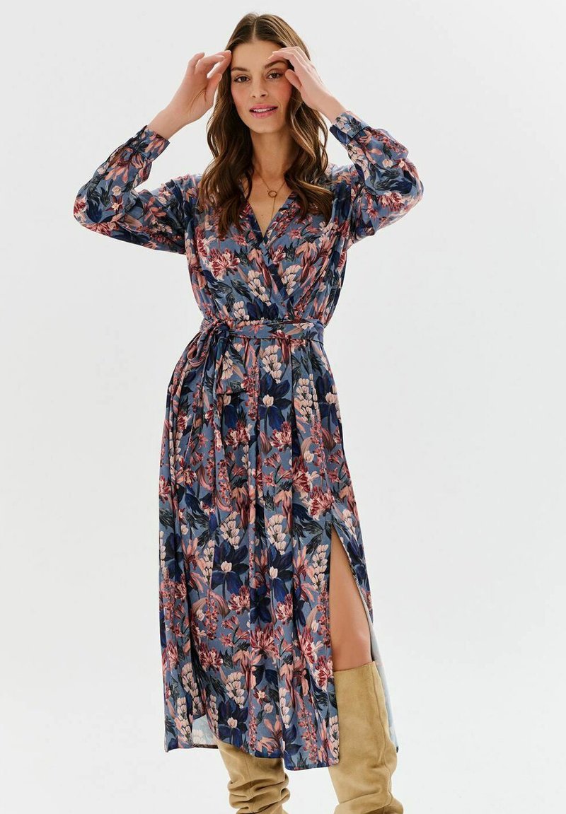 Rochie lungă tip halat cu model floral în nuanțe de bleumarin, roz și verde. Are mâneci lungi, curea în talie și o slită laterală. Material moale și ușor.