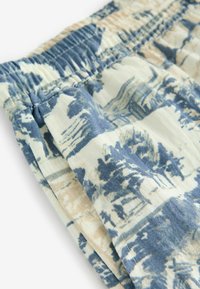 Shorts en tissu avec un motif inspiré de la plage dans des tons de bleu et beige, dotés d'une taille élastique et d'une texture douce.