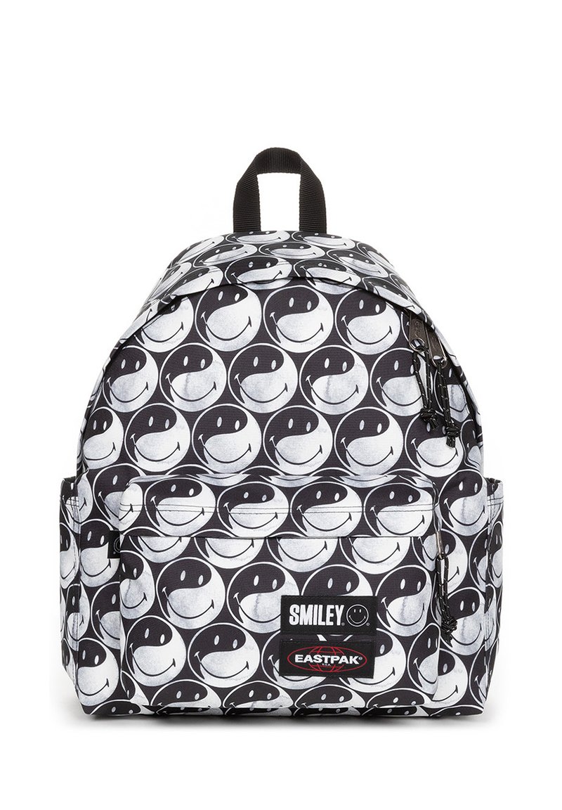 Mochila en blanco y negro con un patrón de caritas sonrientes repetido, fabricada con un tejido de textura duradera. Bolsillo para accesorios con cremallera.