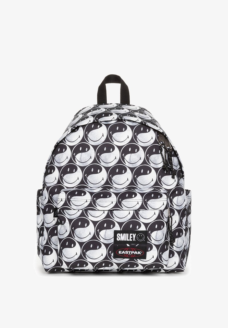 Mochila en blanco y negro con un patrón de caritas sonrientes repetido, fabricada con un tejido de textura duradera. Bolsillo para accesorios con cremallera.