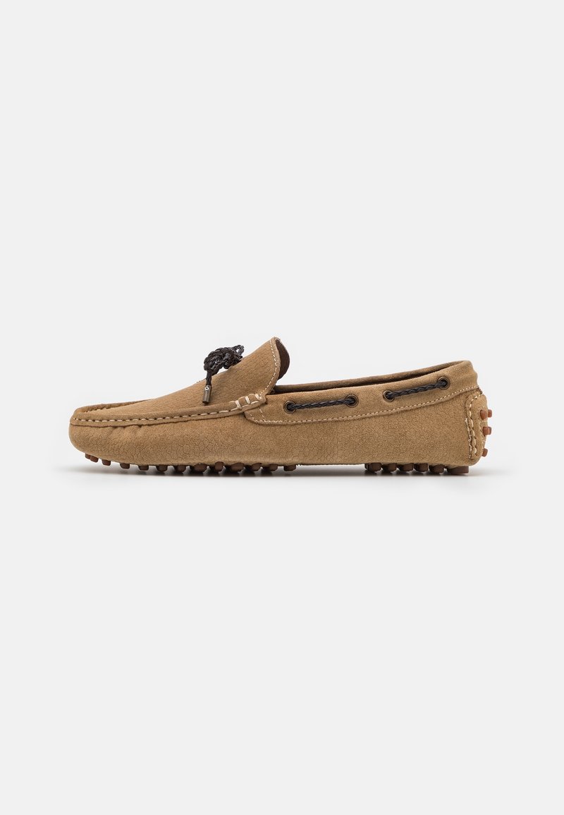 Braune Wildleder-Mokassinschuhe mit abgerundeter Spitze, schwarzen Schnürdetails und einer Gummisohle im Kieselstein-Design für besseren Halt. Keine sichtbaren Muster oder Akzente.
