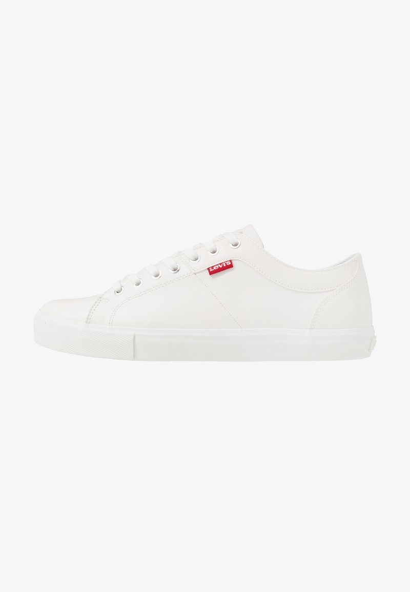 Białe sneakersy wykonane z gładkiego materiału syntetycznego, z zaokrąglonym czubkiem, sześcioma oczkami i czerwonym logo Levi's blisko sznurowadeł. Teksturowana podeszwa.