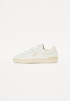 Sneaker bianca in pelle con accenti beige, dettagli perforati e logo oro "REPLAY". Suola in gomma spessa con superficie testurizzata.