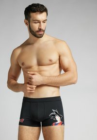 Svarta boxershorts med resårmidja, med en tryckt grafik av en tecknad karaktär på vänster lår.