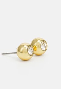 Orecchini a perno sferici color oro con impostazione in strass trasparente. Superficie metallica liscia con una finitura lucida.