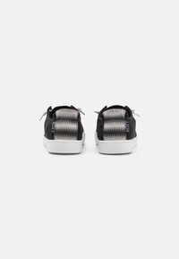 Schwarze Leinensneaker mit einem strukturierten Grau- und Weißakzentmuster an der Ferse, einer weißen Gummisohle und flachen Schnürsenkeln.