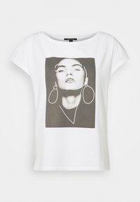 Camiseta blanca de corte holgado, con un estampado gráfico en gris de la cara de una mujer contorneada en blanco. Material de algodón suave y mangas cortas.