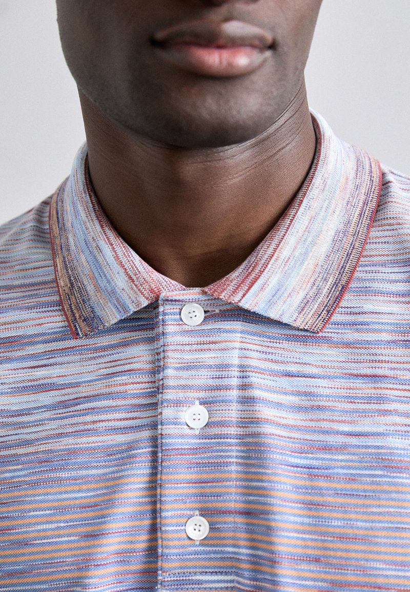 Kurzarm-Poloshirt im gestreiften Design in Blau, Rot und Orange. Mit einer Knopfleiste und einem kontrastierenden Kragen. Aus Baumwollmaterial.